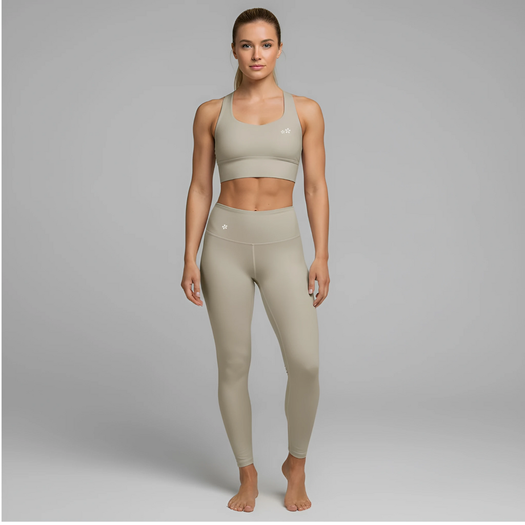 A model showcases the full DuelStars Core Femme sportswear set in stone grey, featuring the high-waisted leggings and matching sports bra with floral detailing.