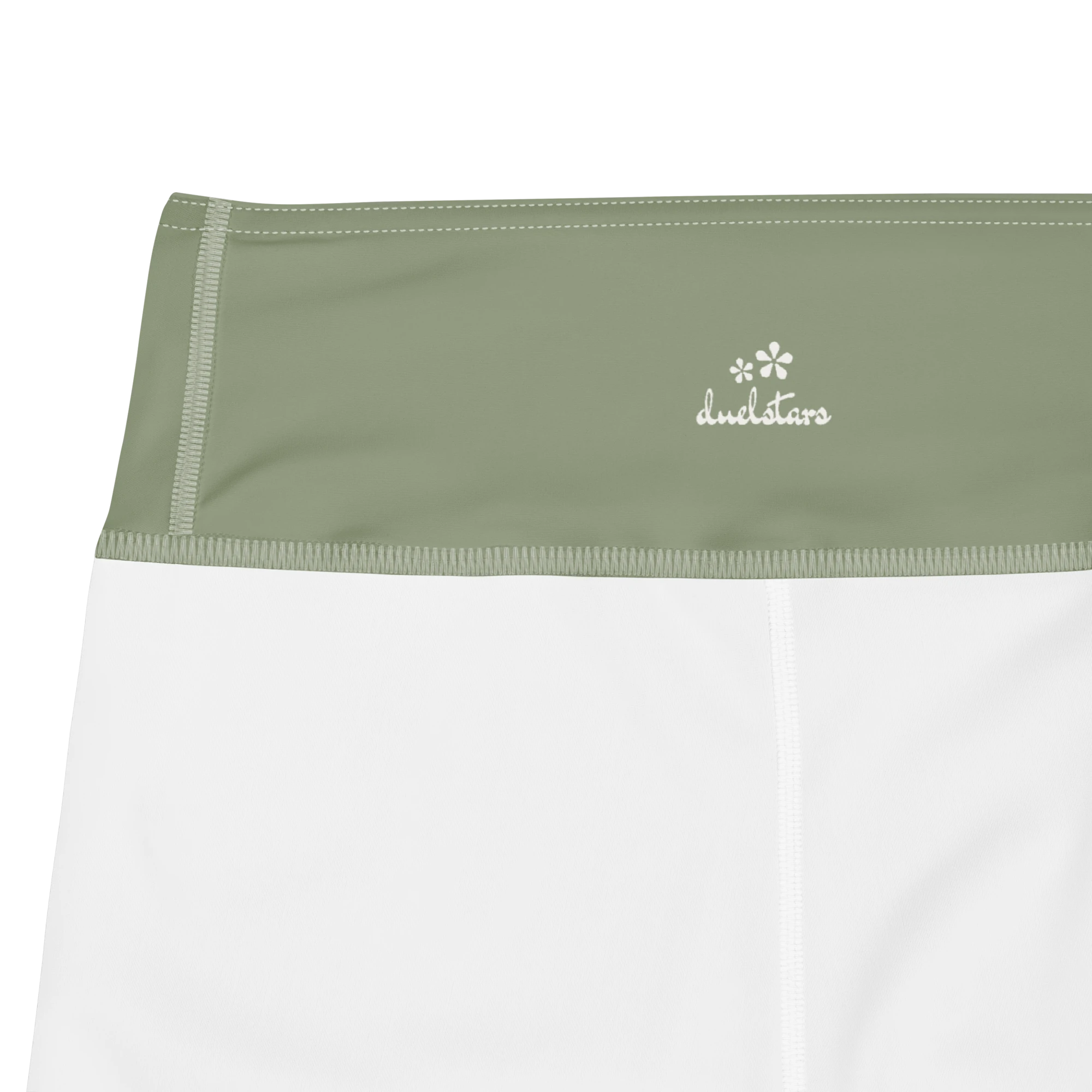 Close-up of the DuelStars label on sage green yoga shorts with ivory white floral print 