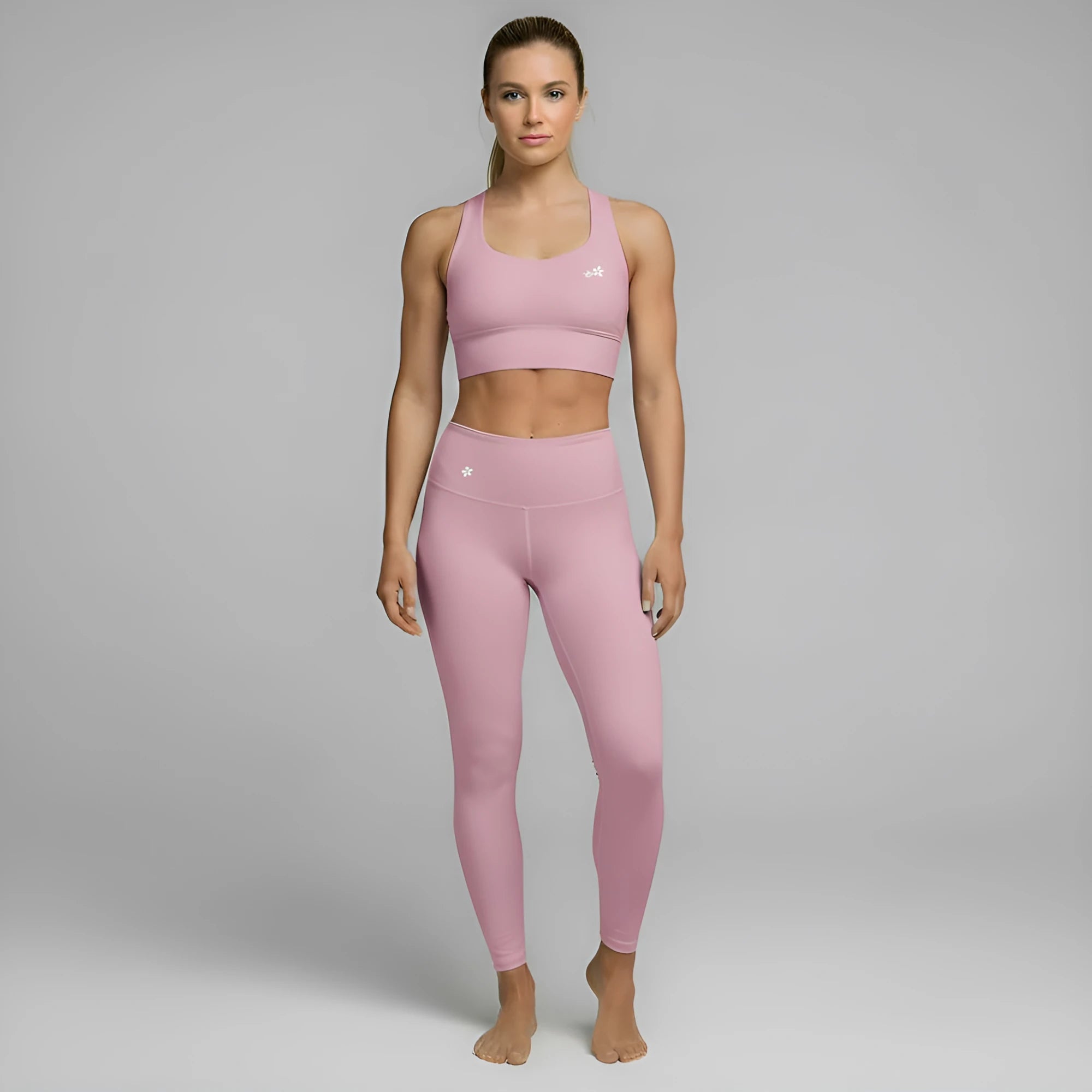 A model showcases the full DuelStars Core Femme sportswear set in dusty rose, featuring the high-waisted leggings and matching sports bra with floral detailing.