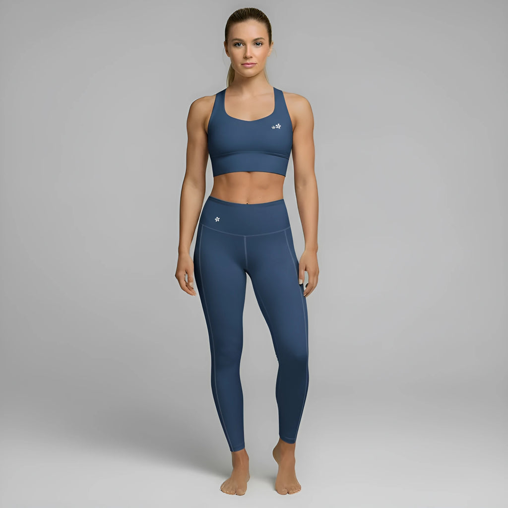 A model showcases the full DuelStars Core Femme sportswear set in ocean blue, featuring the high-waisted leggings and matching sports bra with floral detailing.