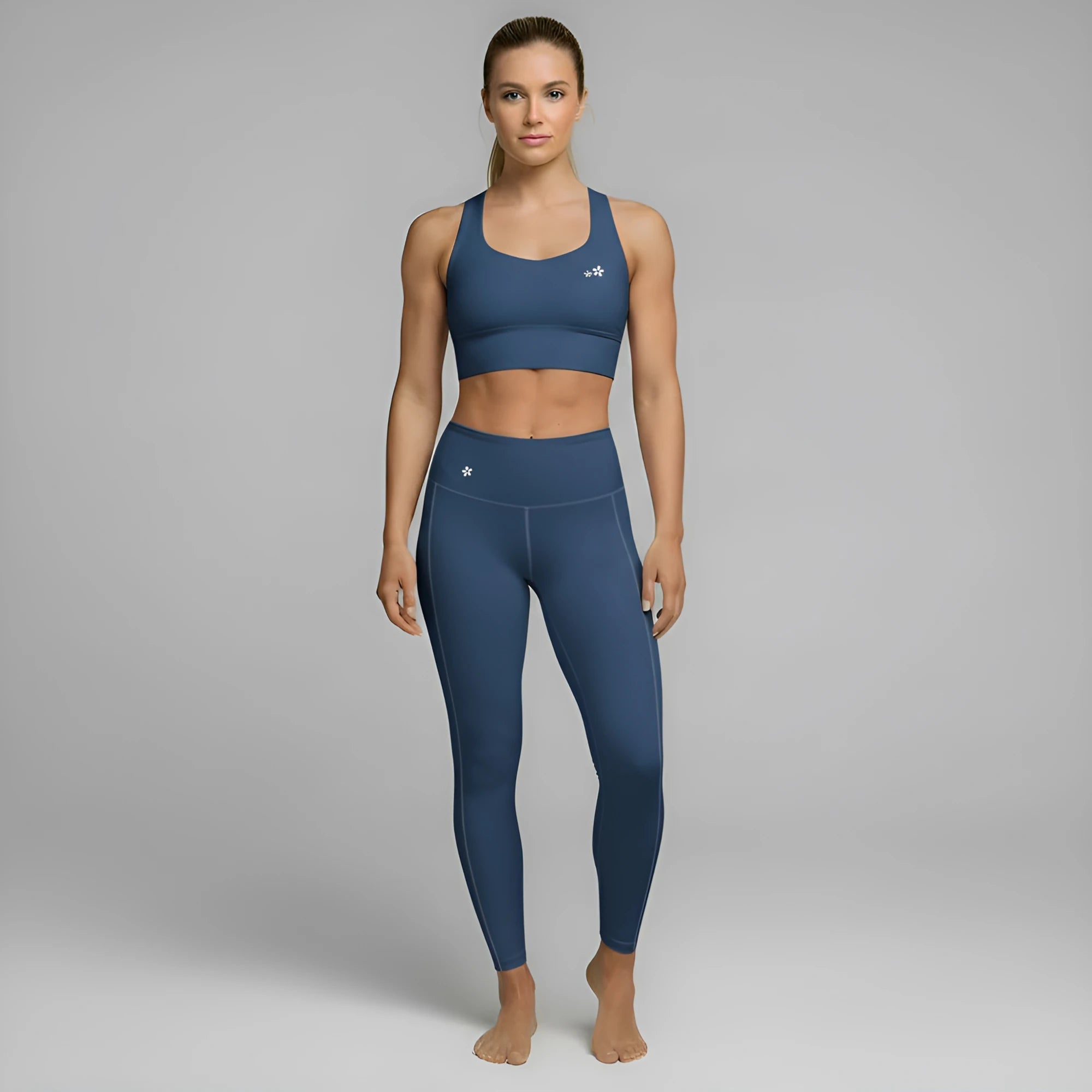 A model showcases the full DuelStars Core Femme sportswear set in ocean blue, featuring the high-waisted leggings and matching sports bra with floral detailing.