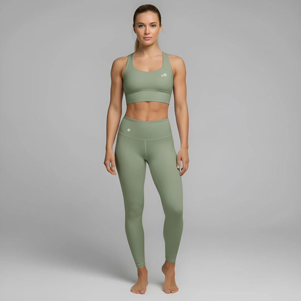 A model showcases the full DuelStars Core Femme sportswear set in sage green, featuring the high-waisted leggings and matching sports bra with floral detailing.